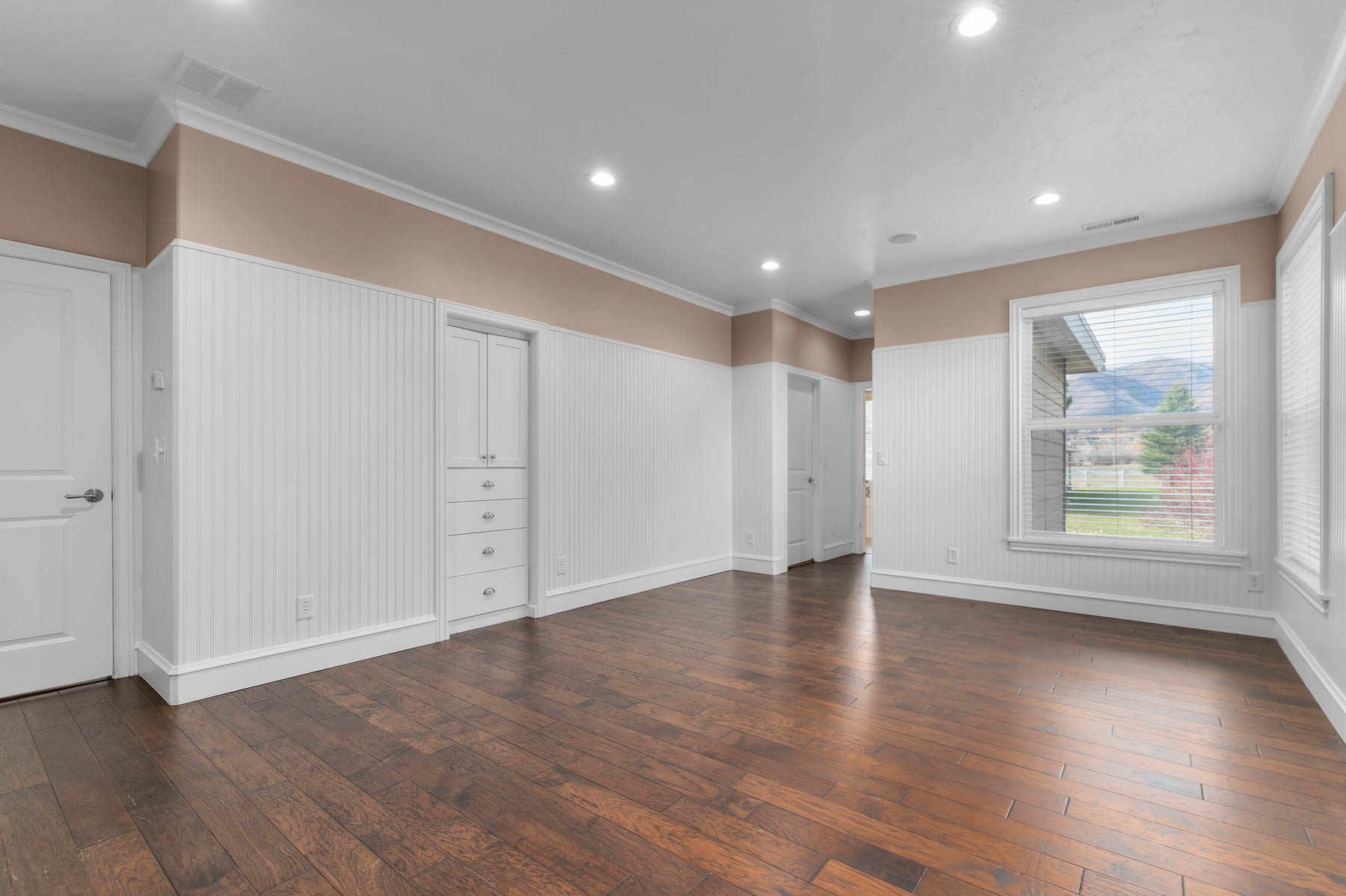 Empty room featuring ornamental molding, dark wood-style flooring, recessed lighting, and wainscoting