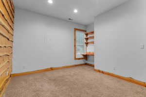 Empty room with light carpet and recessed lighting