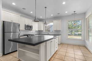 Kitchen with open shelves, backsplash, appliances with stainless steel finishes, light tile patterned flooring, and dark countertops