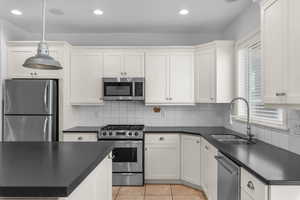 Kitchen featuring appliances with stainless steel finishes, white cabinetry, tasteful backsplash, pendant lighting, and recessed lighting