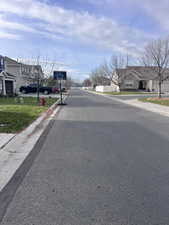 View of asphalt street featuring curbs and a residential view