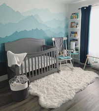 Bedroom with wood finished floors, a nursery area, and a mountain view