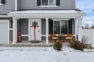 Snow covered property entrance with a porch and a garage