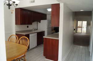 Kitchen with light countertops, white appliances, tasteful backsplash, a chandelier, and a textured ceiling