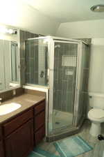 Full master bathroom featuring vanity, a stall shower, lofted ceiling, a textured ceiling, and light wood-style flooring
