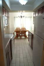 Kitchen featuring stainless steel appliances, light countertops, and a chandelier