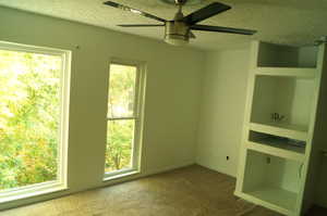 Carpeted master bedroom with a textured ceiling and a ceiling fan