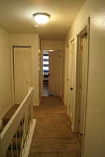 Corridor with an upstairs landing and carpet flooring