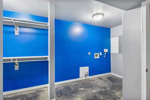 Laundry area featuring a textured ceiling, washer hookup, and concrete floors