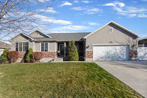 View of front facade with brick siding, concrete driveway, a front yard, a porch, and stucco siding