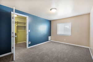 Unfurnished bedroom featuring a spacious closet, a textured ceiling, and carpet flooring