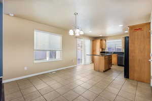 Kitchen with pendant lighting, a chandelier, a center island, dishwasher, and dark stone counters