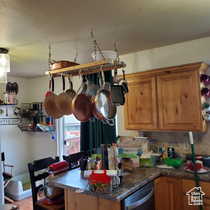Kitchen with brown cabinetry, backsplash, dishwasher, a peninsula, and dark stone countertops