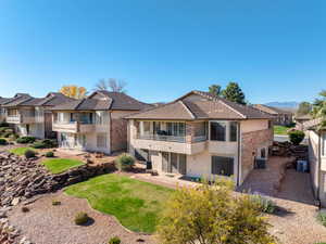 Rear view of property featuring a balcony, a yard, stucco siding, and a patio