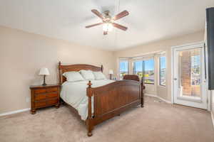 Carpeted bedroom with access to outside and ceiling fan
