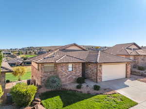 View of front of property featuring brick siding, concrete driveway, an attached garage, a tile roof, and a front lawn