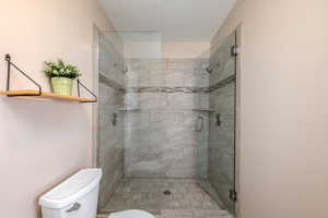 Bathroom with a shower stall and a textured ceiling