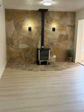 Detailed view of the natural gas stove highlighting hand crafted rock fireplace, wood finished floors, with tasteful sconces