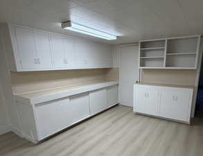 Bar area with white cabinetry, light countertops, light wood finished floors, and open shelves