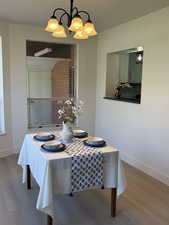 Dining/Sunroom depicting viewing window into the kitchen, with light laminate wood flooring and a chandelier