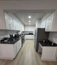 Kitchen with beautiful white cabinetry featuring brushed gold trim & brand new stainless steel appliances, tasteful subway backsplash, and recessed lighting