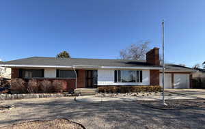 Ranch-style house with brick siding, xeriscaped front yard,, covered porch, concrete driveway, and a garage