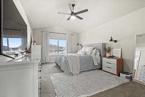 Carpeted bedroom featuring vaulted ceiling and a ceiling fan