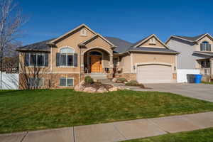 View of front of home featuring stucco siding, driveway, stone siding, and an attached garage