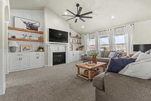 Living room featuring a glass covered fireplace, light carpet, a ceiling fan, high vaulted ceiling, and recessed lighting