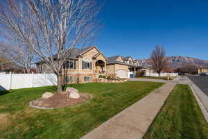 View of front of house featuring a mountain view, stone siding, stucco siding, driveway, and an attached garage