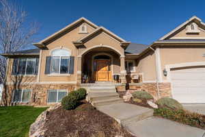 View of front of home with stone siding, stucco siding, and a garage