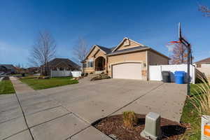 View of front of property featuring concrete driveway, stone siding, stucco siding, and a garage