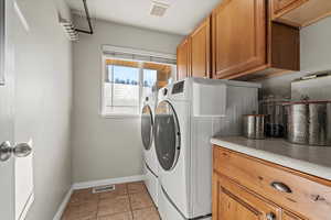 Laundry area featuring light tile patterned floors, washing machine and dryer, and cabinet space