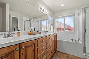Bathroom featuring double vanity, a bath, a shower stall, dark tile patterned flooring, and recessed lighting