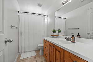 Bathroom featuring a shower with shower curtain, vanity, and light tile patterned floors