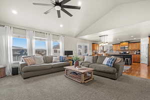 Living room with vaulted ceiling, recessed lighting, a chandelier, a ceiling fan, and wood finished floors