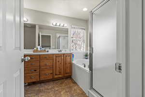 Full bathroom featuring a stall shower, a garden tub, and vanity