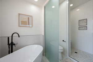 Bathroom featuring a freestanding bath, recessed lighting, marble finish flooring, tiled shower, and tile walls