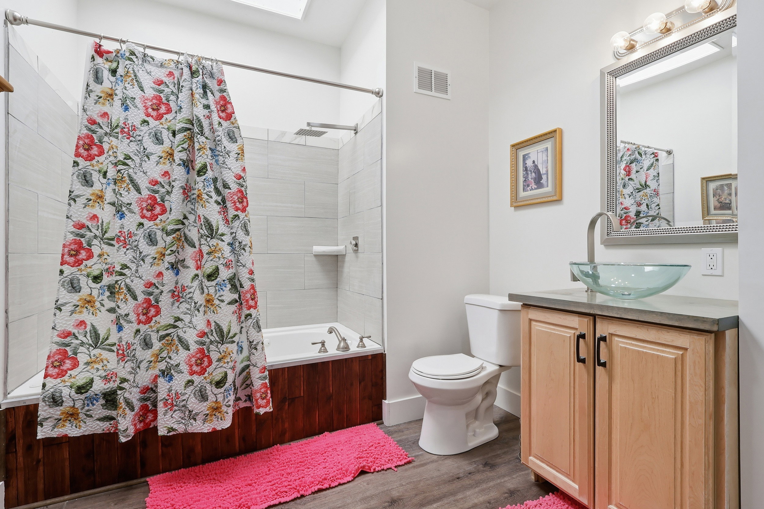 Bathroom with vanity, shower / tub combo with curtain, wood finished floors, and a skylight