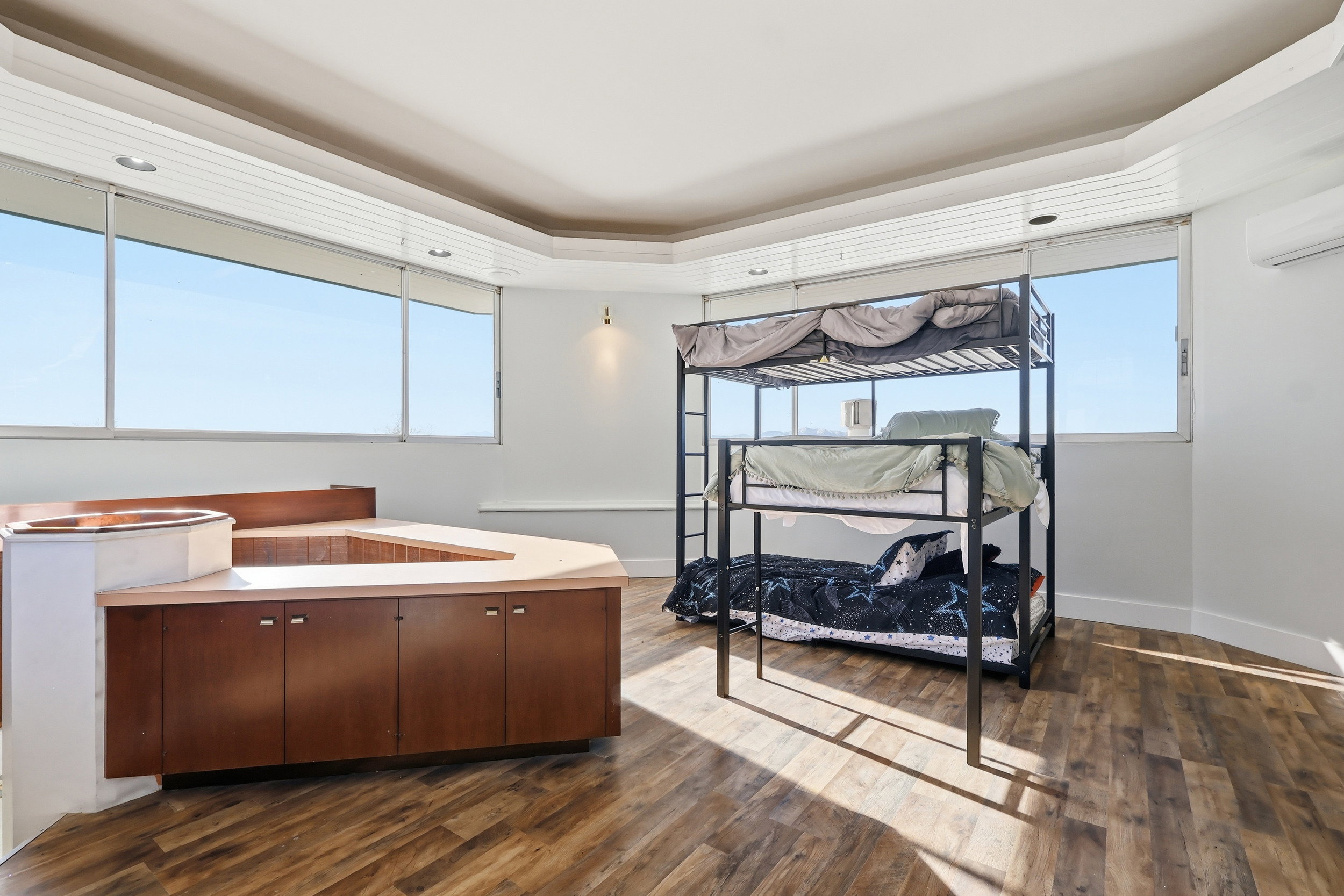 Bedroom featuring a tray ceiling, dark wood-style flooring, and a wall mounted AC