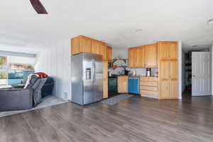 Kitchen with stainless steel fridge with ice dispenser, open floor plan, dishwasher, black stove, and light brown cabinets