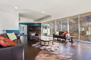 Living area featuring expansive windows, a raised ceiling, recessed lighting, and wood finished floors