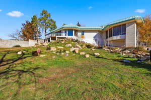 Back of house featuring a standing seam roof, a metal roof, a yard, and a balcony