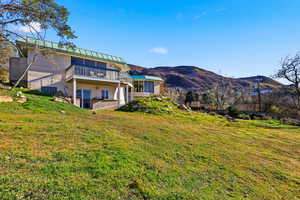 Back of property with a standing seam roof, a metal roof, a yard, and a mountain view