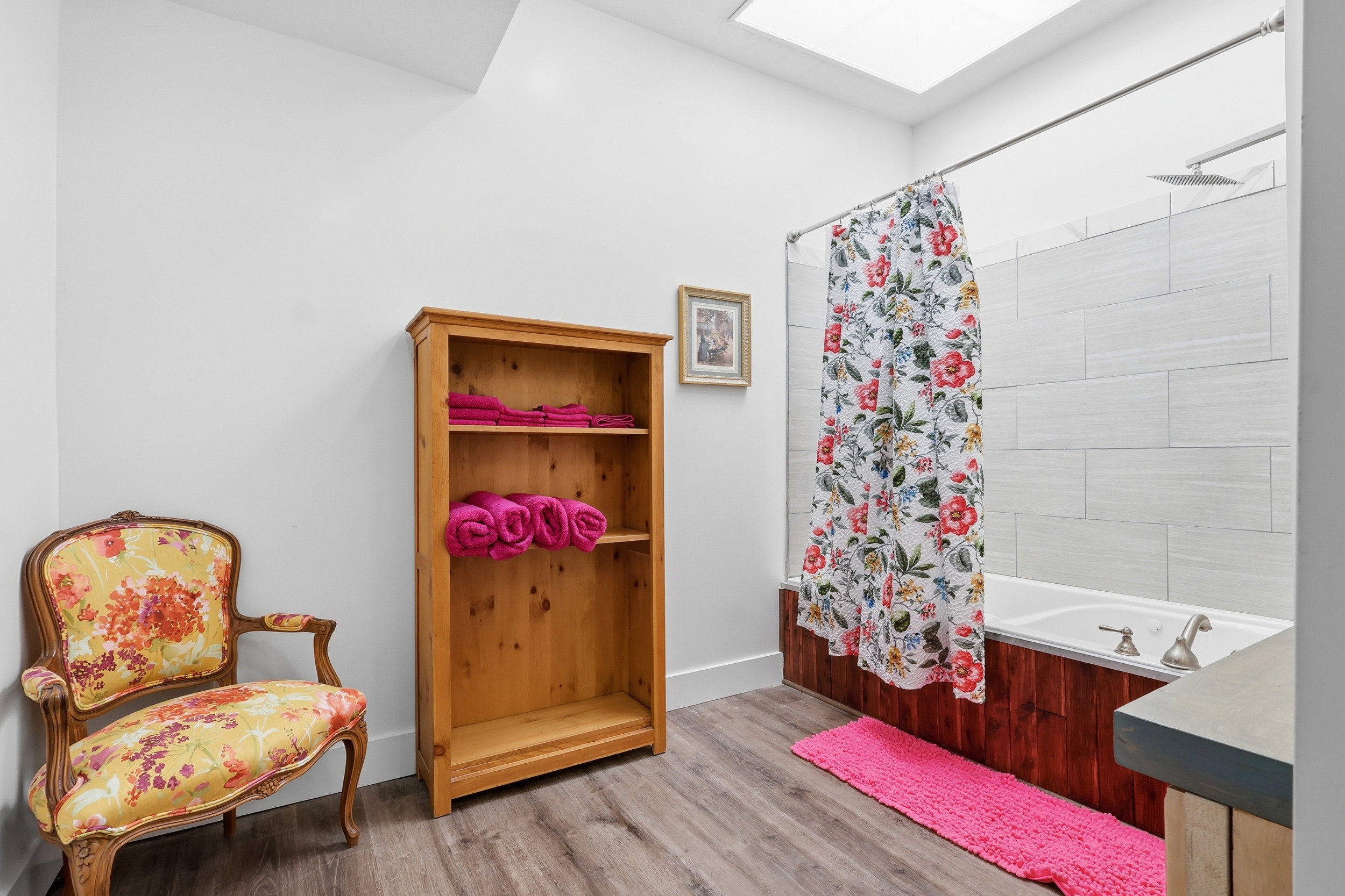 Full bath with shower / bathtub combination with curtain, light wood-style flooring, and a skylight