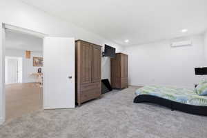 Bedroom featuring an AC wall unit and light carpet
