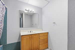 Full bathroom featuring a textured wall, vanity, and a shower with curtain