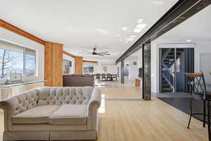 Living room with light wood finished floors, a ceiling fan, stairs, and recessed lighting