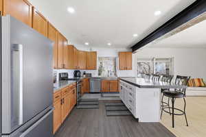 Kitchen with a kitchen bar, appliances with stainless steel finishes, dark wood finished floors, recessed lighting, and dark countertops