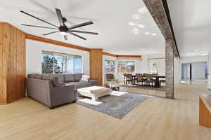 Living room with light wood-type flooring, recessed lighting, and wooden walls